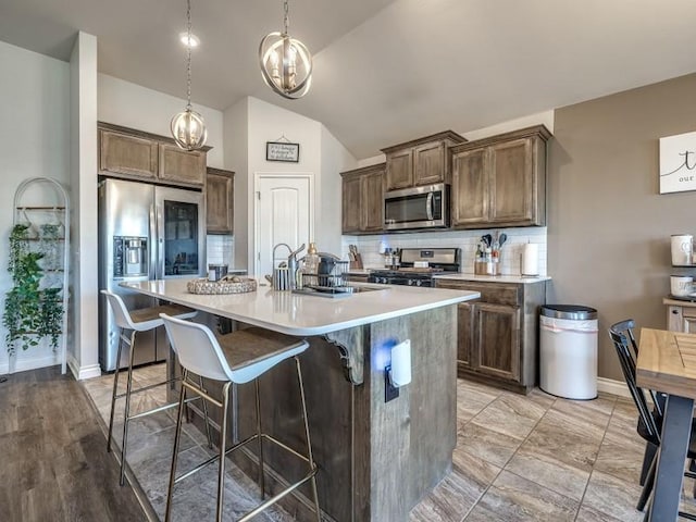 kitchen with light countertops, appliances with stainless steel finishes, a sink, and tasteful backsplash