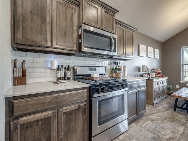 kitchen with tasteful backsplash, appliances with stainless steel finishes, vaulted ceiling, and light countertops