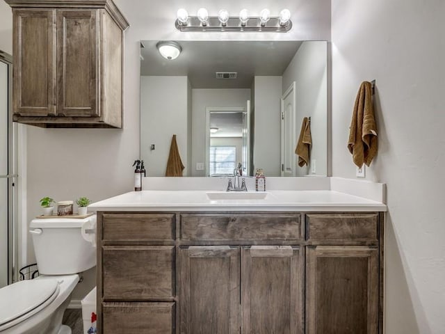 bathroom with toilet, vanity, and visible vents