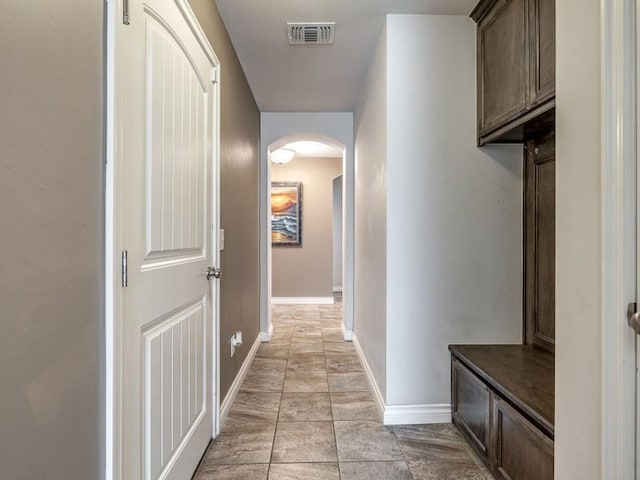 hallway with baseboards, visible vents, and arched walkways