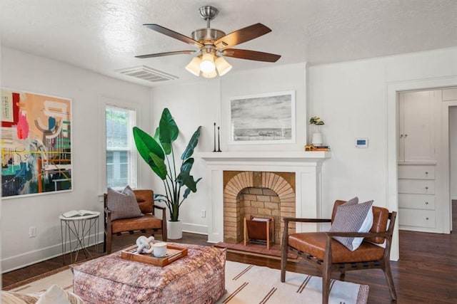 sitting room featuring a brick fireplace, wood finished floors, visible vents, and baseboards