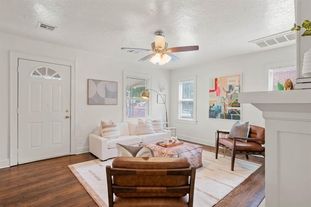 living room with a textured ceiling, wood finished floors, visible vents, and baseboards