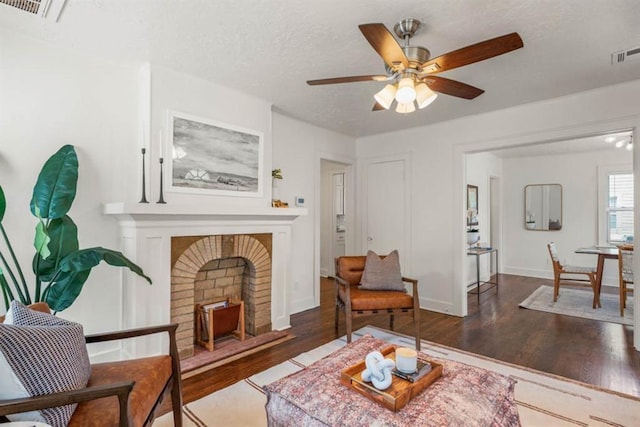 living room with baseboards, a textured ceiling, visible vents, and wood finished floors