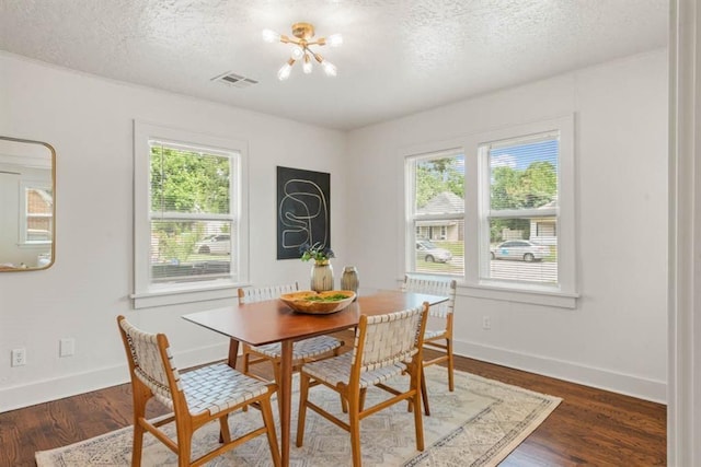 dining area featuring a textured ceiling, dark wood-type flooring, visible vents, and a healthy amount of sunlight