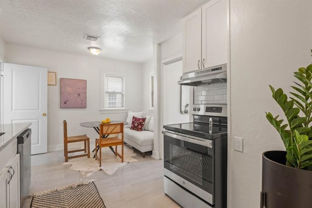 kitchen featuring backsplash, appliances with stainless steel finishes, white cabinets, a textured ceiling, and under cabinet range hood