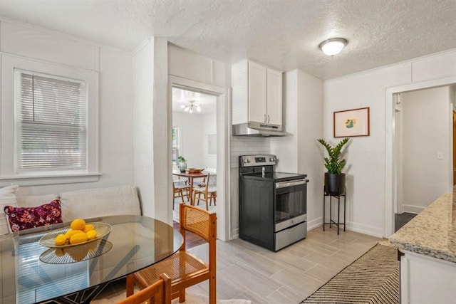 kitchen with light stone counters, stainless steel electric stove, breakfast area, white cabinetry, and under cabinet range hood