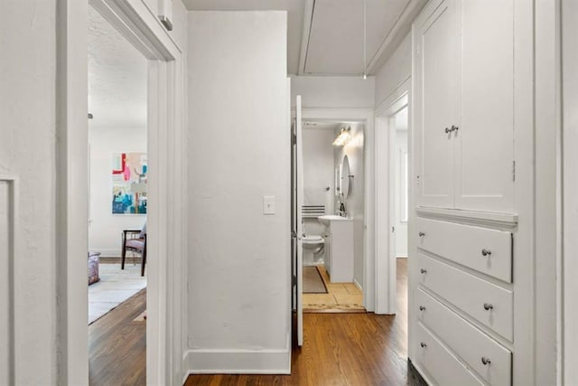 corridor featuring attic access, dark wood finished floors, and baseboards