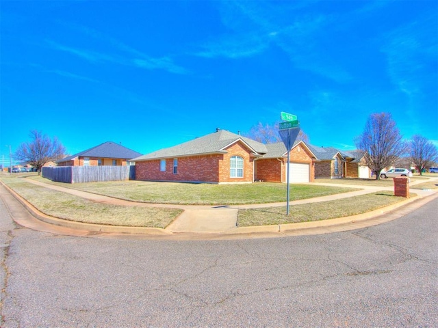 single story home with an attached garage, brick siding, fence, concrete driveway, and a front lawn