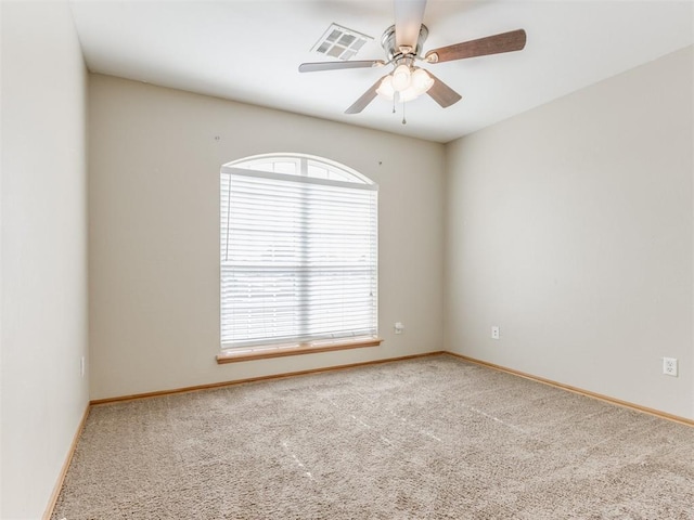 carpeted spare room with baseboards, visible vents, and a ceiling fan