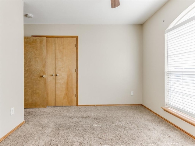 unfurnished bedroom featuring carpet floors, a ceiling fan, baseboards, and a closet