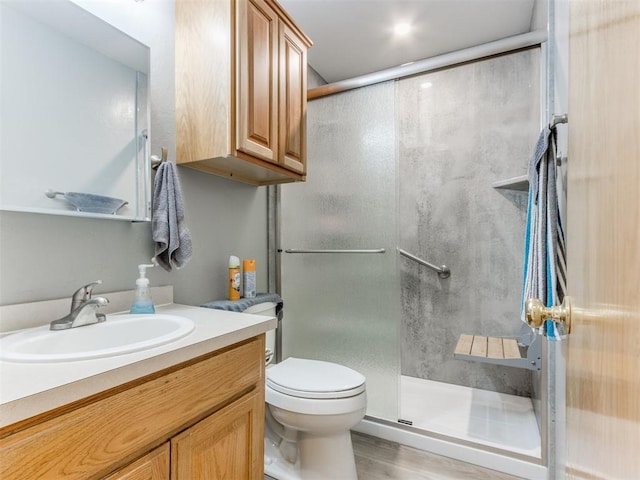 full bathroom featuring wood finished floors, a shower stall, toilet, and vanity