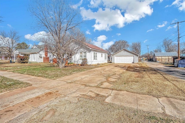 view of front of property featuring a garage, a front yard, and an outbuilding