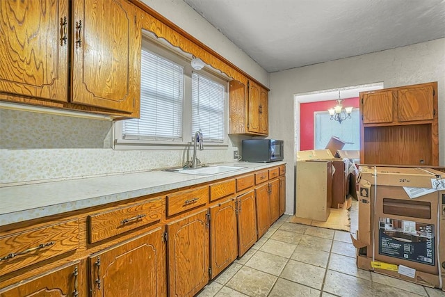 kitchen featuring brown cabinets, light countertops, a sink, washer and dryer, and black microwave