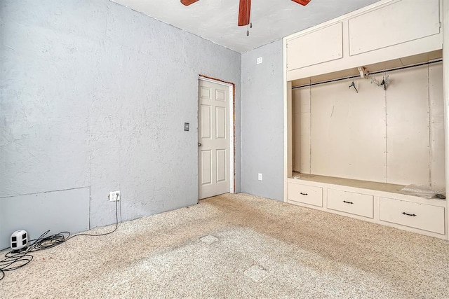 unfurnished bedroom with a ceiling fan, carpet, and a textured wall