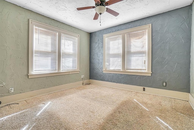 carpeted spare room featuring a textured ceiling, a wealth of natural light, and a textured wall