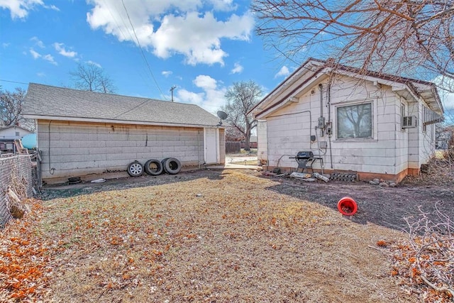 view of side of property with a shingled roof and fence