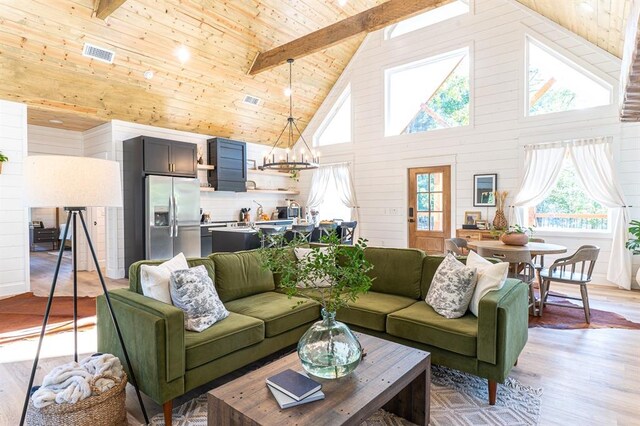 living area with visible vents, wooden ceiling, light wood-style flooring, beamed ceiling, and an inviting chandelier