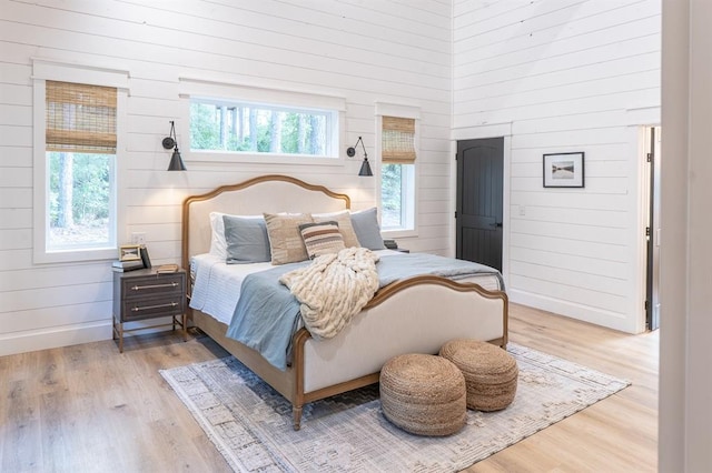 bedroom featuring wooden walls, baseboards, and wood finished floors