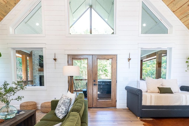 living room with high vaulted ceiling, french doors, wood finished floors, and wooden walls