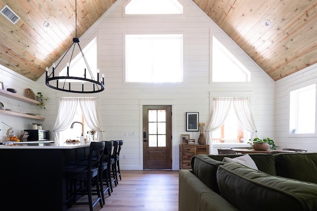 living area featuring a chandelier, wood ceiling, visible vents, and wood finished floors