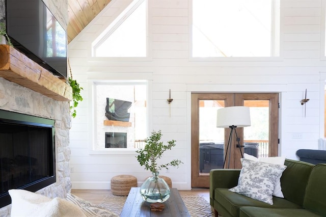 living room with high vaulted ceiling, wood finished floors, plenty of natural light, and a glass covered fireplace