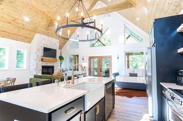 kitchen with wood ceiling, open floor plan, stainless steel appliances, light countertops, and high vaulted ceiling