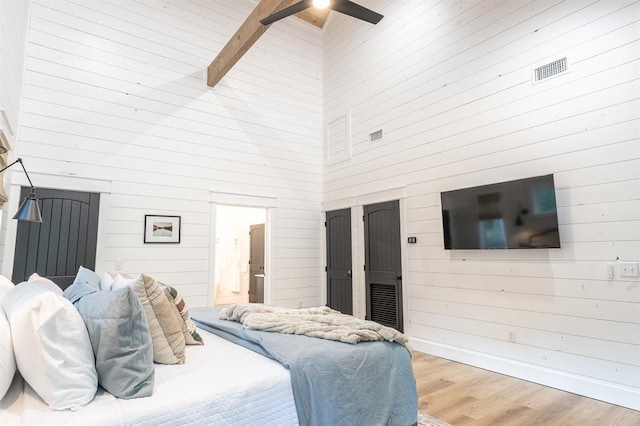 bedroom with high vaulted ceiling, light wood-style flooring, visible vents, baseboards, and beamed ceiling