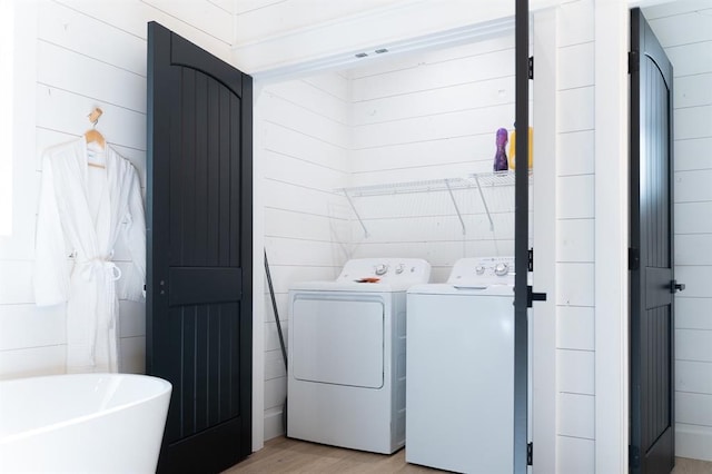 laundry room with light wood-type flooring, laundry area, independent washer and dryer, and tile walls