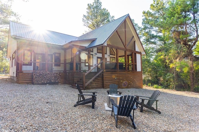 back of house featuring stairs, metal roof, and a sunroom