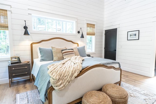 bedroom with wood walls and wood finished floors