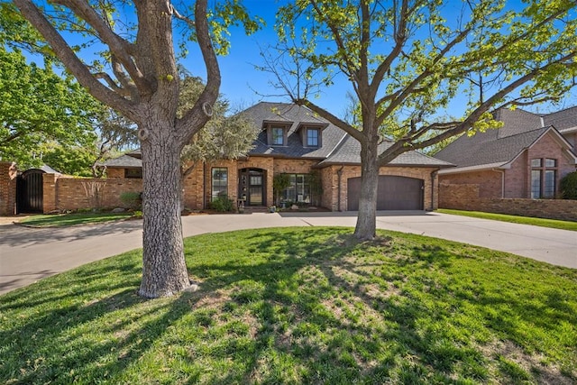 traditional-style home featuring fence, an attached garage, brick siding, a front yard, and driveway
