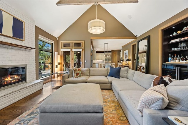 living room featuring high vaulted ceiling, a dry bar, a brick fireplace, and wood finished floors