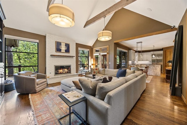 living area with a fireplace, wood finished floors, high vaulted ceiling, and beamed ceiling