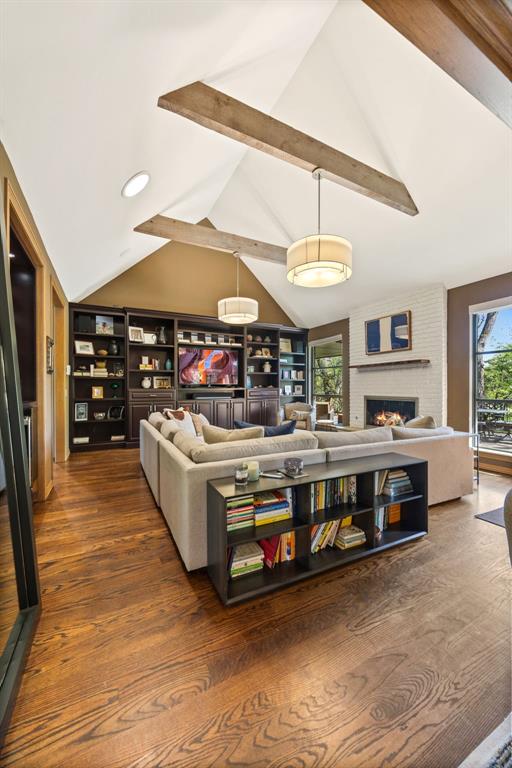 living area with vaulted ceiling with beams, a brick fireplace, recessed lighting, and wood finished floors