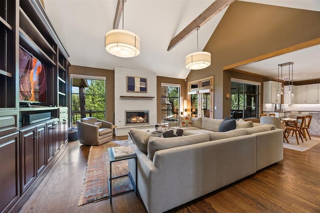 living room featuring dark wood-type flooring, high vaulted ceiling, a fireplace, and beamed ceiling