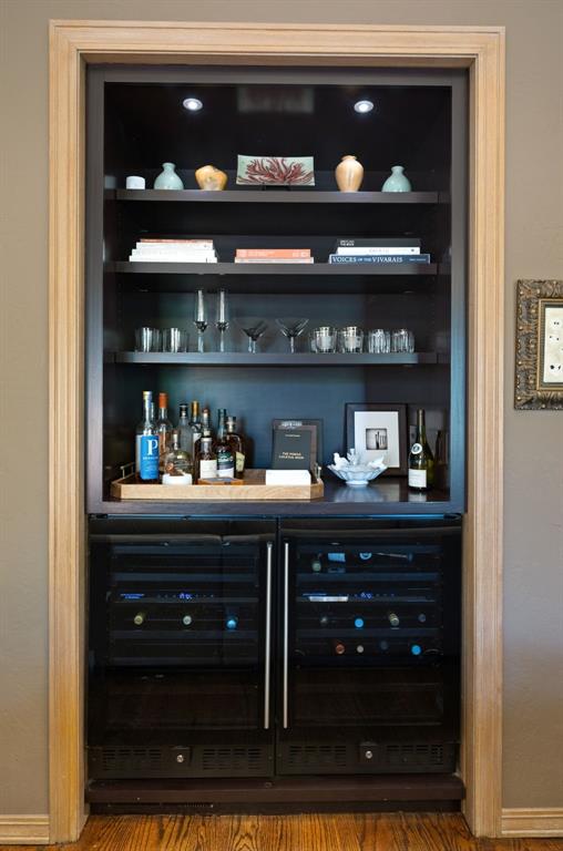 bar with a bar, baseboards, wine cooler, and wood finished floors