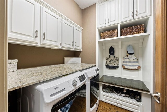 washroom featuring washing machine and dryer, cabinet space, and wood finished floors
