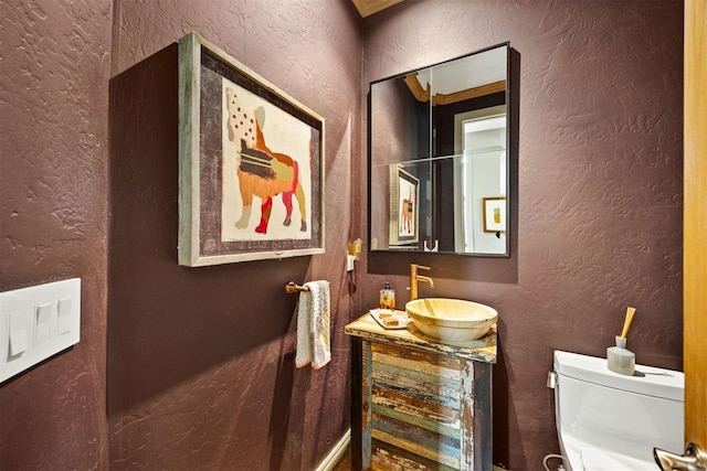 bathroom with vanity, a textured wall, and toilet