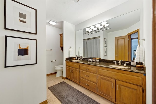 full bathroom featuring a sink, tile patterned flooring, toilet, and double vanity