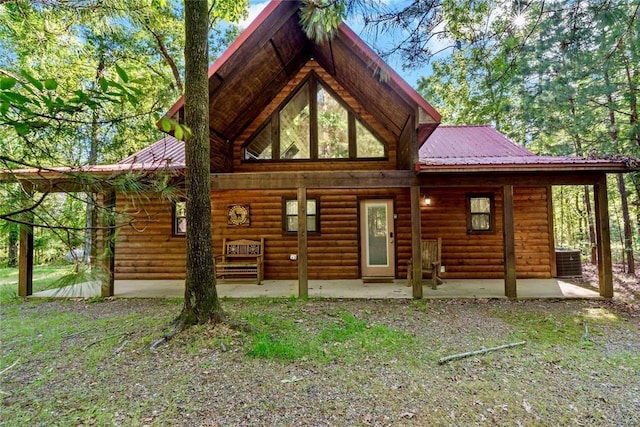 back of house featuring a patio area, faux log siding, central AC, and metal roof