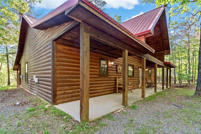 view of side of property with metal roof, log veneer siding, and a patio area