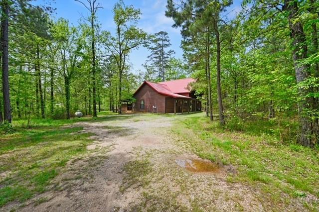 view of home's exterior featuring a forest view and dirt driveway