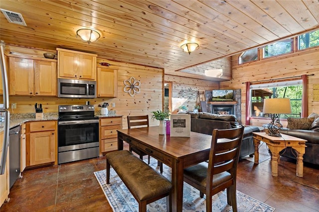 kitchen with appliances with stainless steel finishes, wood ceiling, wooden walls, and light brown cabinetry