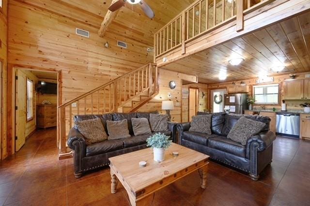 living room with wooden ceiling, wooden walls, a high ceiling, and stairway