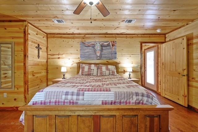 bedroom featuring wooden ceiling, visible vents, and wooden walls