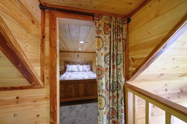 unfurnished bedroom featuring wood walls, wood ceiling, and carpet