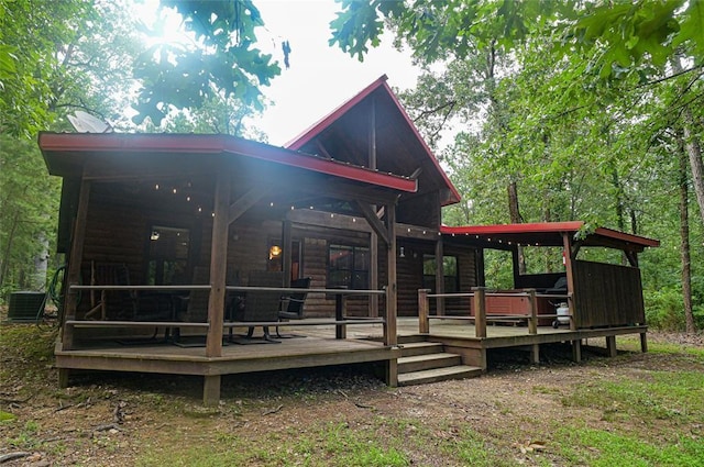 rear view of house with log veneer siding, a deck, and central AC unit