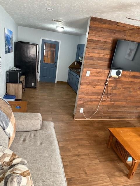 living area featuring visible vents, a textured ceiling, and wood finished floors