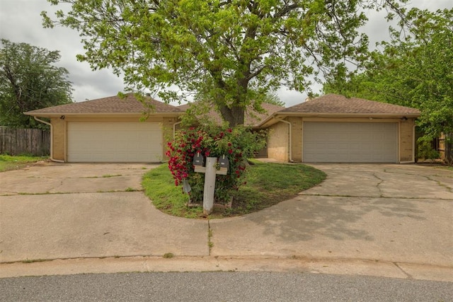 single story home with a detached garage, brick siding, and fence