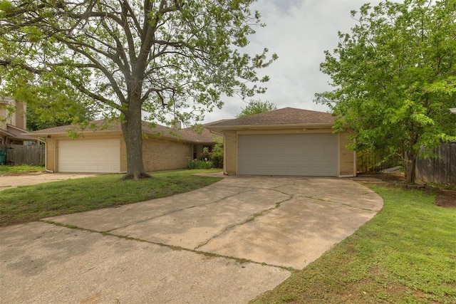 ranch-style house featuring a front yard, fence, and a detached garage